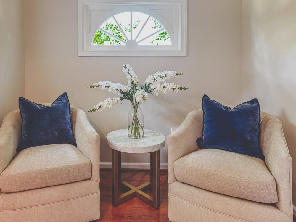 Two cream chairs with navy pillows, styled vignette