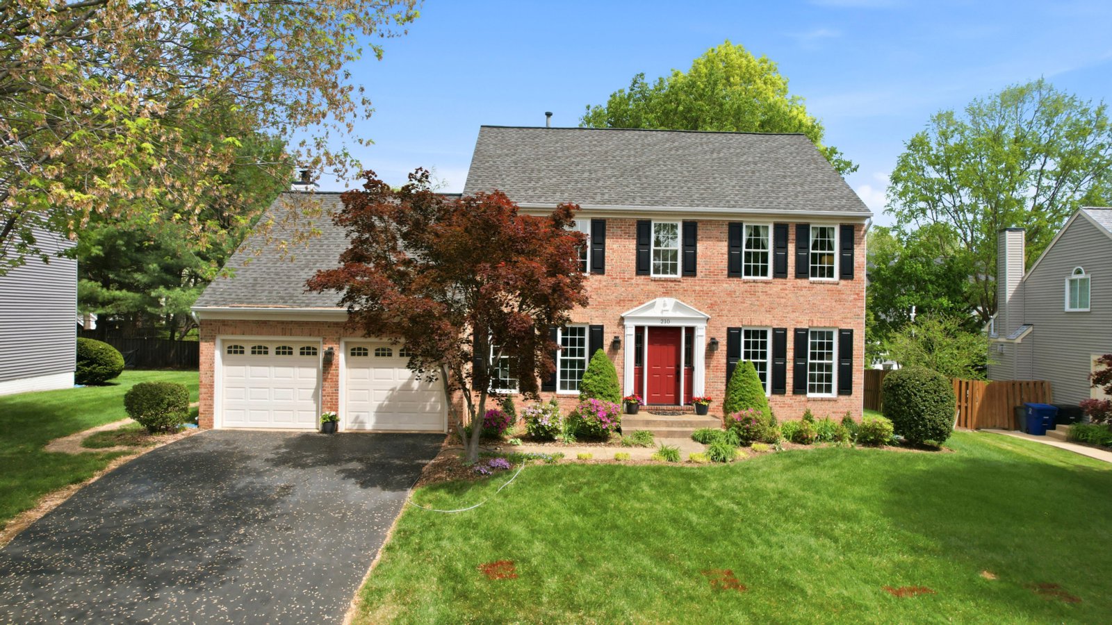 Brick colonial with red door on a landscaped lot